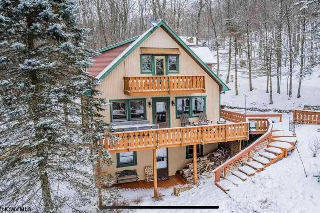 a large house with a deck in the snow at 3 Bedroom Cabin at Alpine Lake, near Deep Creek-WISP Resort in Terra Alta