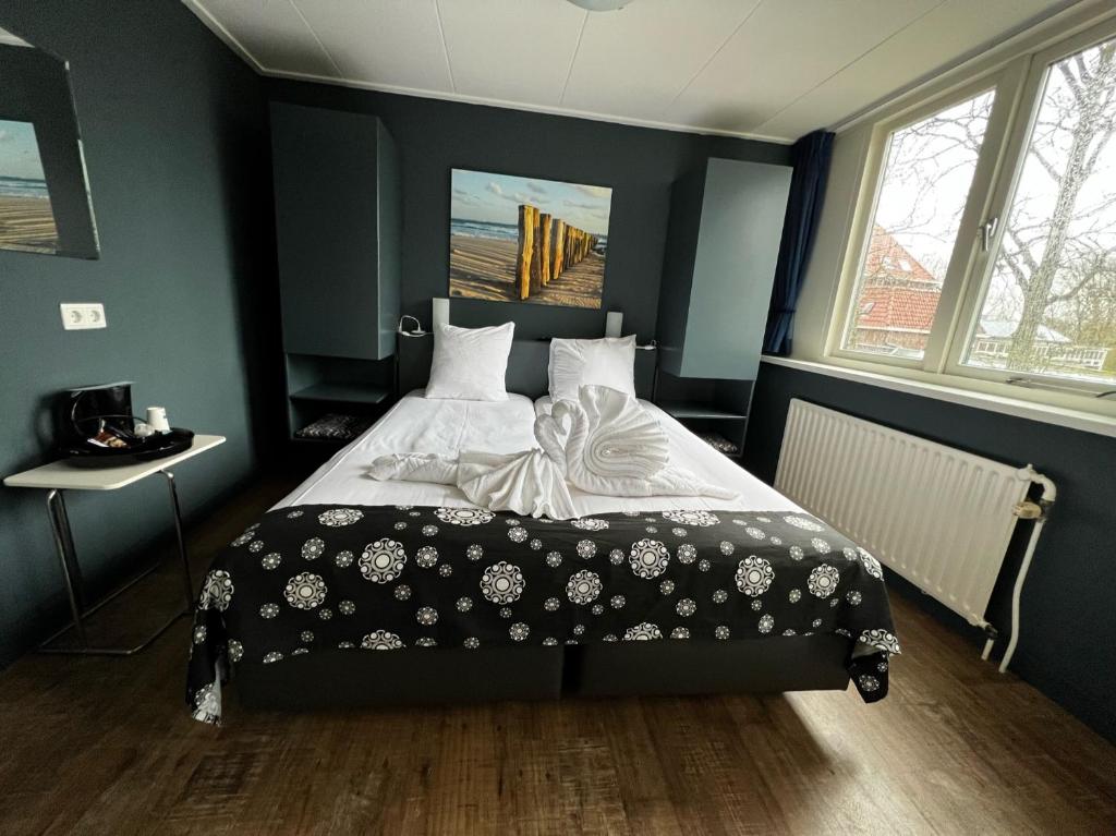 a bedroom with a bed with a black and white blanket at Hotel Huys ter Schelde in Koudekerke