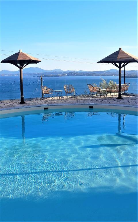 una piscina con sedie e ombrelloni accanto all'acqua di Stefanosplace ApartHotel Sea View a Barbati