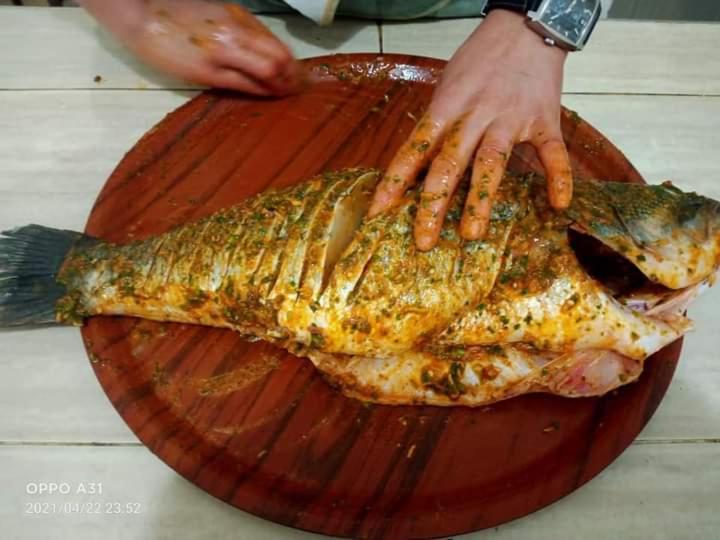 a person reaching for a fish on a wooden plate at دوار ابغاوة ازغيرة تروال سد الوحدة وزان in Srija