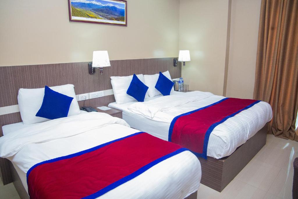two beds in a hotel room with blue and red sheets at Hotel Span in Butwāl