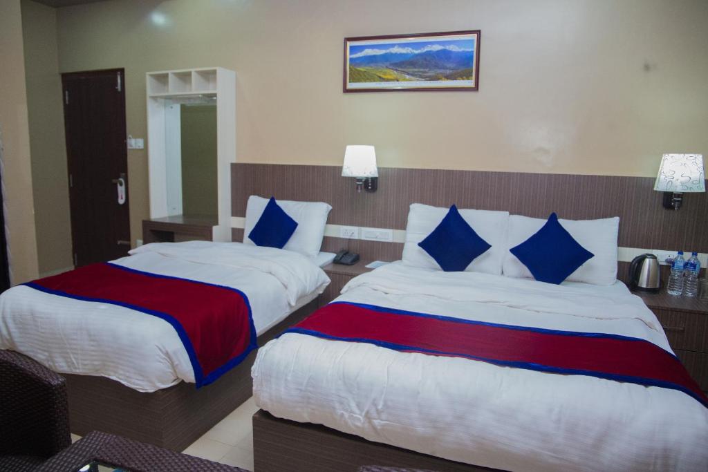 a hotel room with two beds with blue and red sheets at Hotel Span in Butwāl