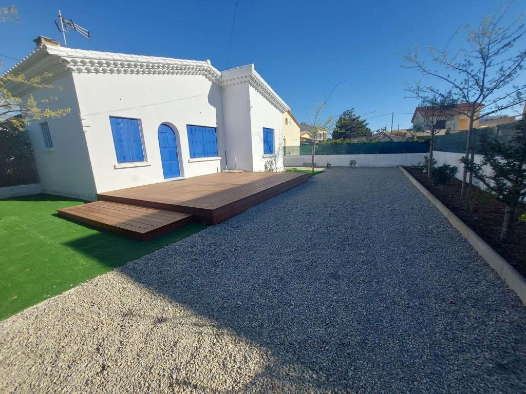 dom z drewnianym tarasem przed nim w obiekcie Maison chaleureuse 3 pièces à 60m de la plage avec jardin et terrasse barbecue - FR-1-326-772 w mieście Marseillan