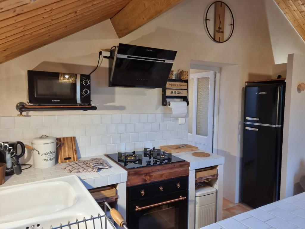a kitchen with a black refrigerator and a stove at La Ferme de Philomène - Gîte en Périgord Noir in Sainte-Foy-de-Belvès