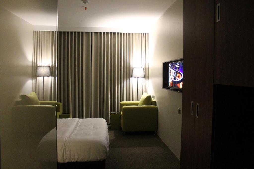 a hotel room with a bed and two chairs and a television at High Village Hotel in Al Namas