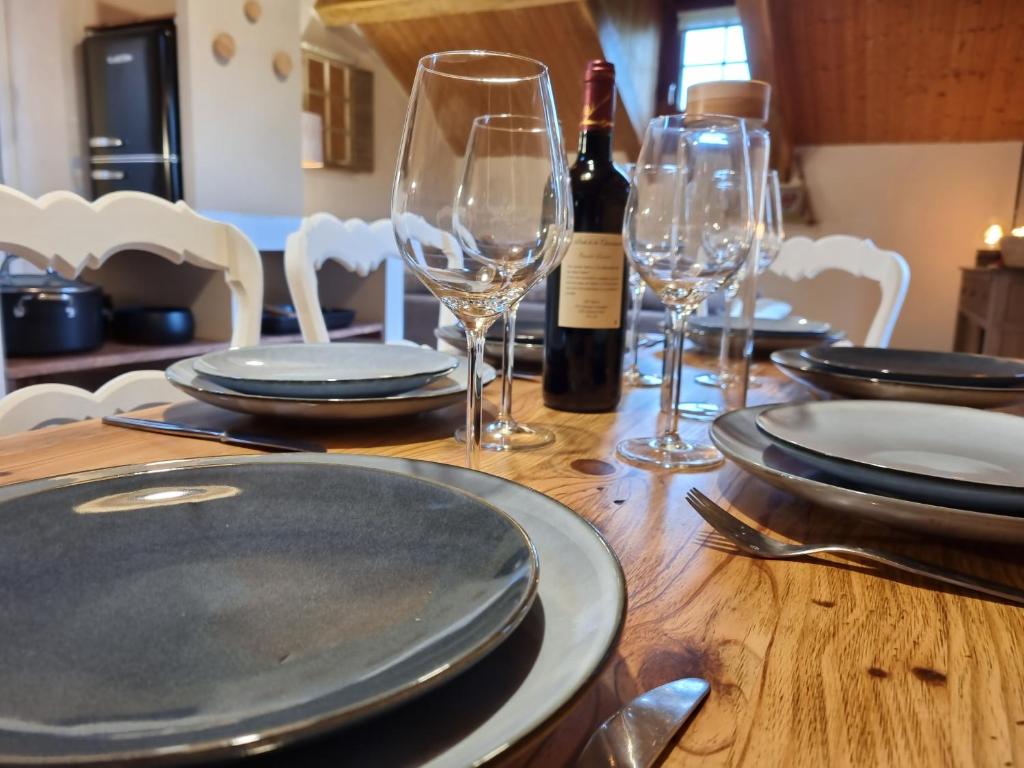 a wooden table with plates and wine glasses on it at La Ferme de Philomène - Gîte en Périgord Noir in Sainte-Foy-de-Belvès