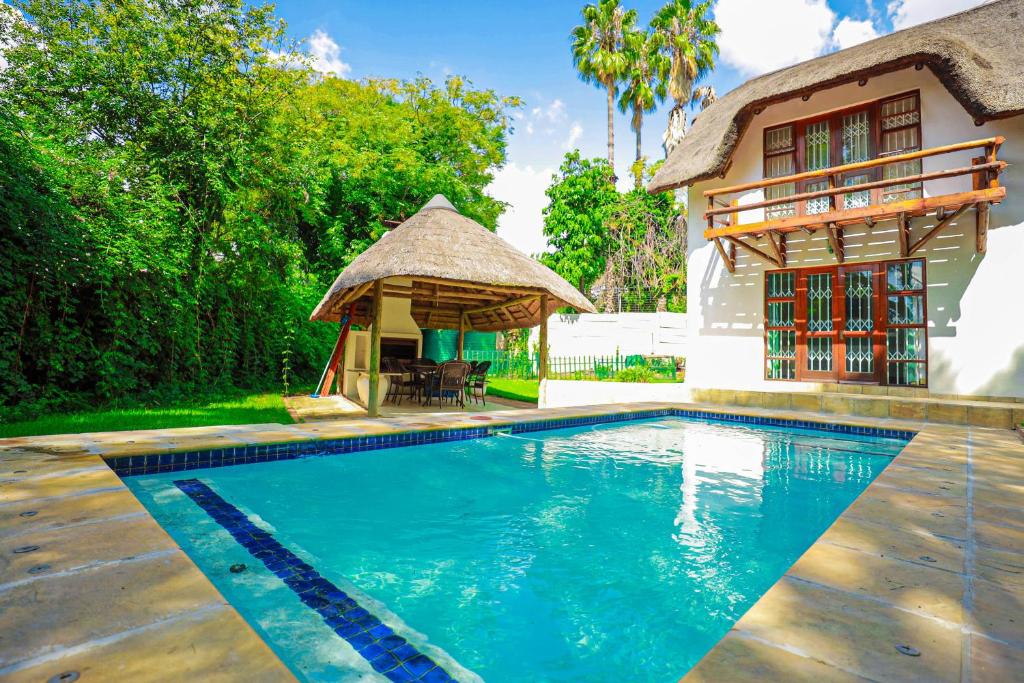 a swimming pool in front of a house with a gazebo at Charming Country Villa Sandton with Back Up Power & Water in Johannesburg