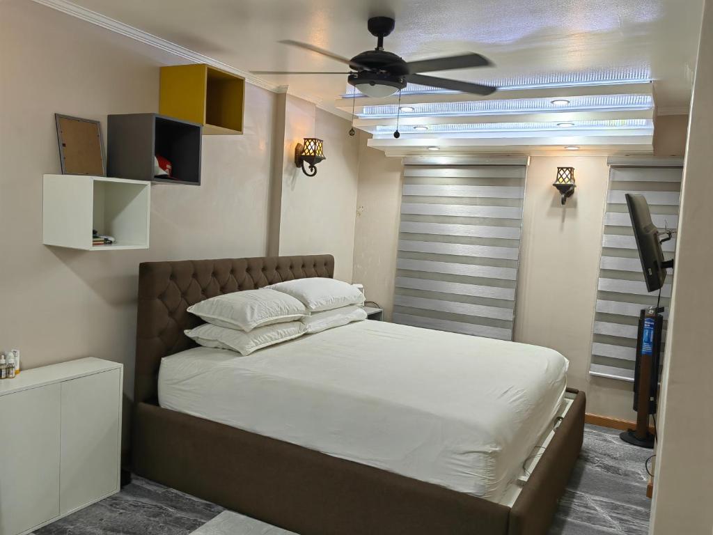 een slaapkamer met een bed en een plafondventilator bij You Can afford To Dwell Well in Manilla