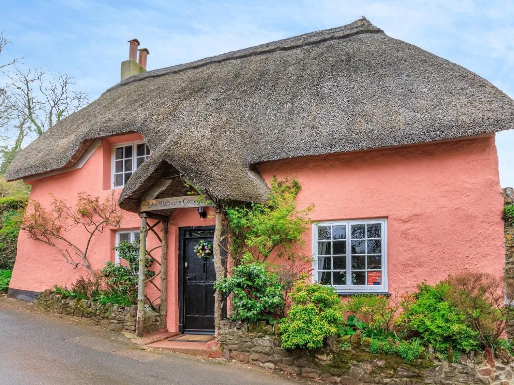 a pink cottage with a thatched roof at Weavers Cottage in Torquay