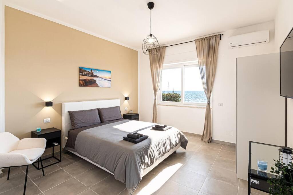 a bedroom with a bed and a chair and a window at Esclusivo alloggio a sfioro sul mare con terrazza. in Santa Maria di Castellabate