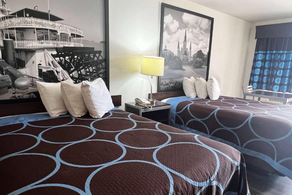a hotel room with a bed and a painting on the wall at Super 8 by Wyndham Slidell in Slidell