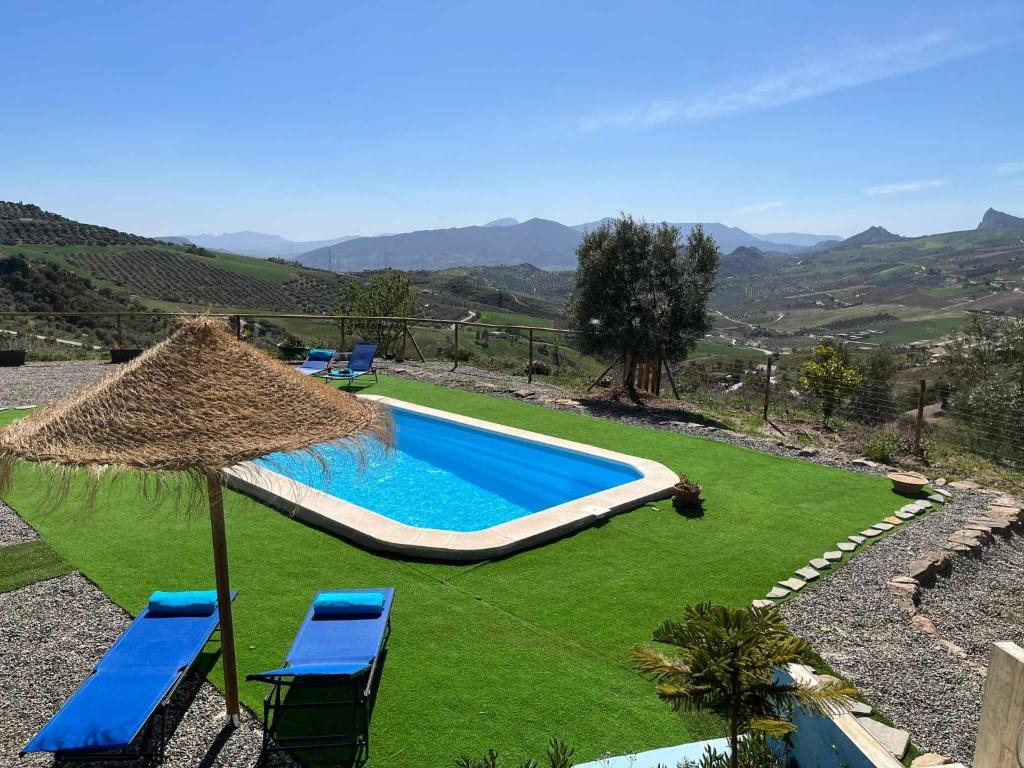 een zwembad met twee blauwe stoelen en een parasol bij Mirador de Shilpa y Sonal in Valle de Abdalagís