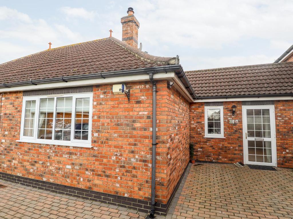 een stenen huis met witte ramen en een dak bij Tawny Owl Cottage in Louth