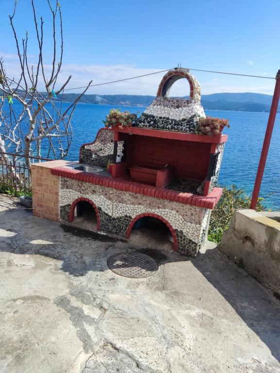 a stone fireplace with a bench in front of the water at Venia's House in Ammouliani