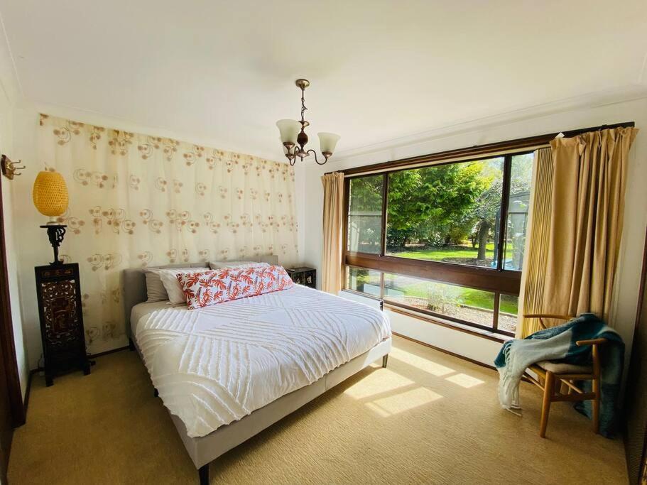 a bedroom with a bed and a large window at Relaxing at acreage farmhouse in Burrawang