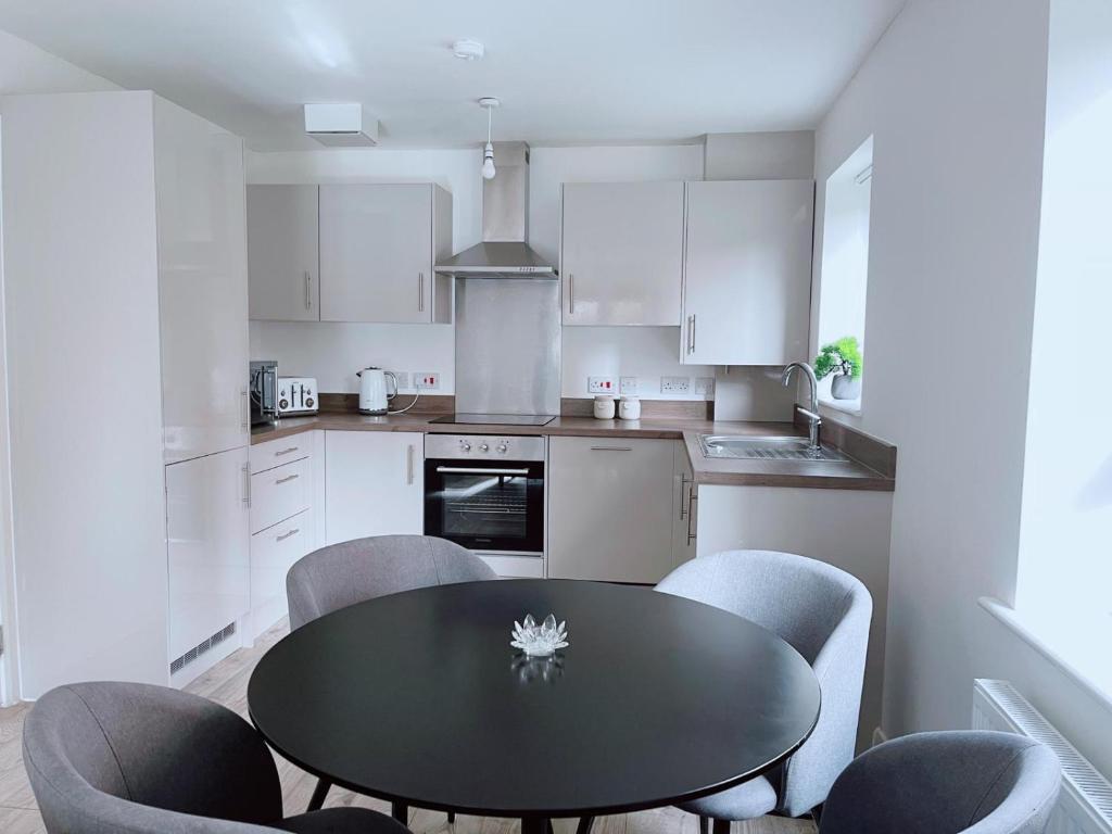 a kitchen with a black table and chairs in it at Shared Modern Apartment Double Bedroom With Attached Bath in Manchester