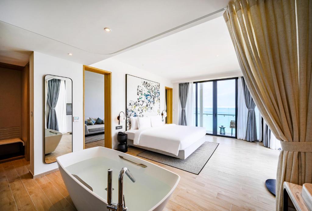 uma casa de banho com uma cama e uma banheira num quarto em Anya Premier Hotel Quy Nhon em Quy Nhon
