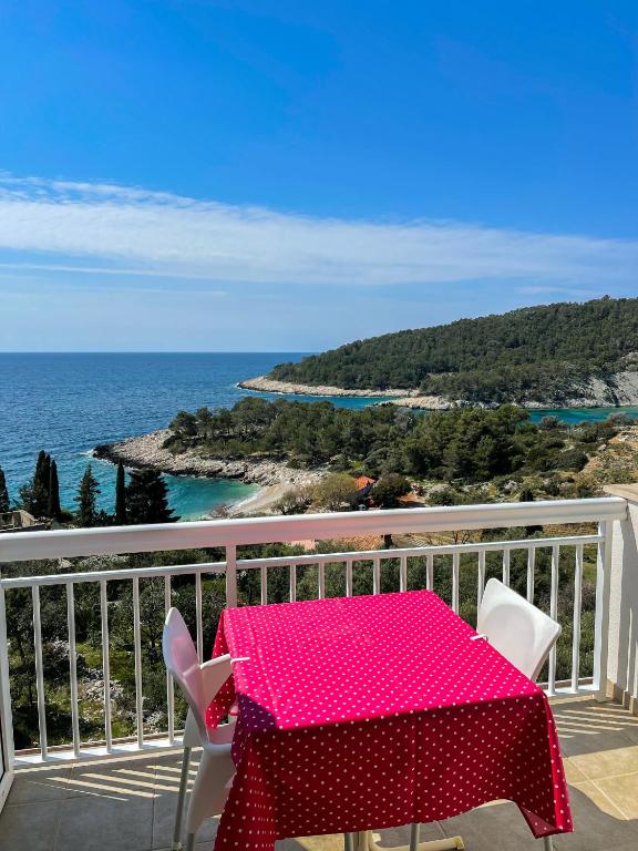 a pink table and chairs on a balcony with the ocean at Apartments Marija Magdalena in Hvar