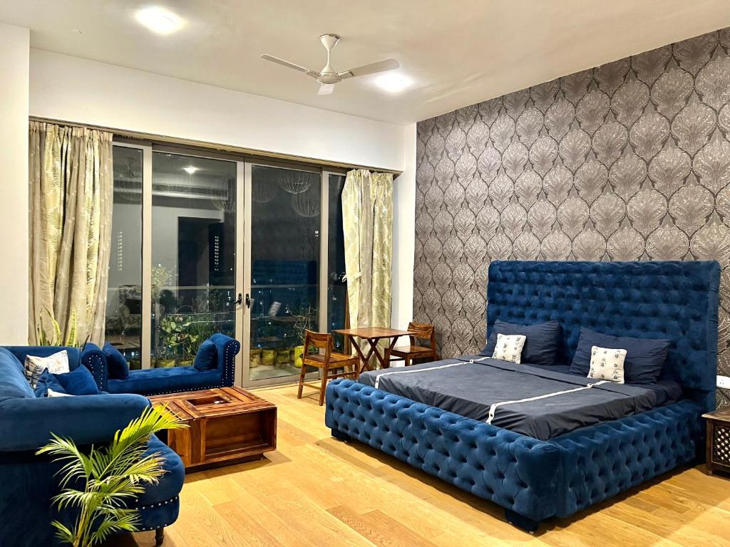 uma sala de estar com um sofá azul e uma cama em luxury master bedroom with bathtub n private entry best for parties em Nova Deli