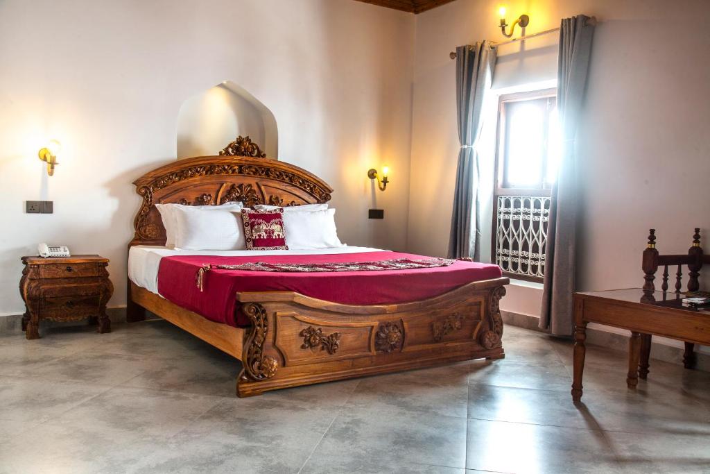 a bedroom with a large wooden bed and a window at Tembo House Hotel in Zanzibar City