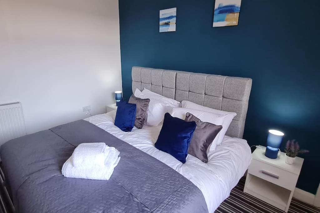 a bedroom with a large bed with blue walls at Bury Stays in Bury