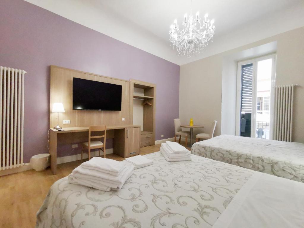1 dormitorio con 2 camas, escritorio y TV en Opera Relais 85, en Messina