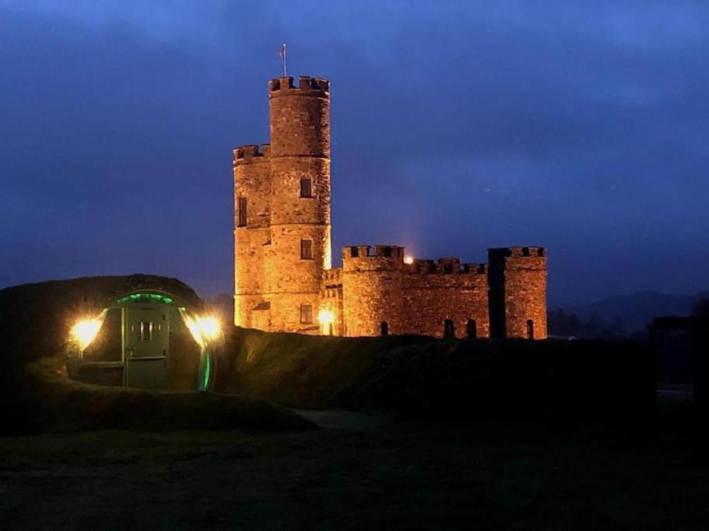 ein Schloss in der Nacht mit eingeschaltetem Licht in der Unterkunft Romantic Rural Break In Countryside Castle Grounds Private Retreat Wizards Rest in Bishops Tawton