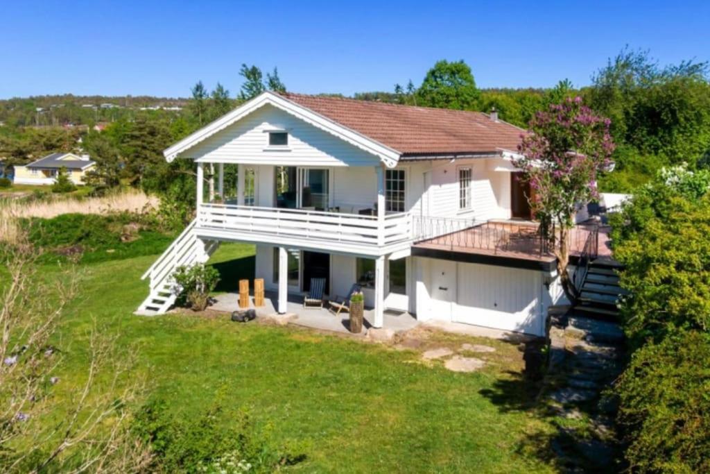 uma casa branca com um alpendre e um quintal em Summer house on Tjøme with beach and pier em Tjome