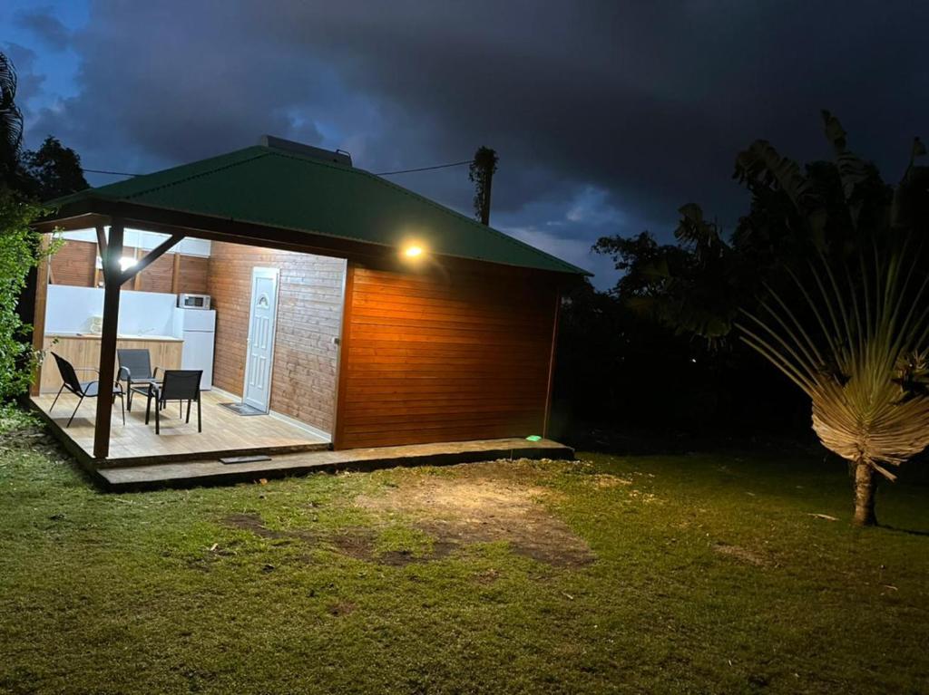 une petite maison avec un toit vert la nuit dans l'établissement Nature et quiétude, à Le Moule