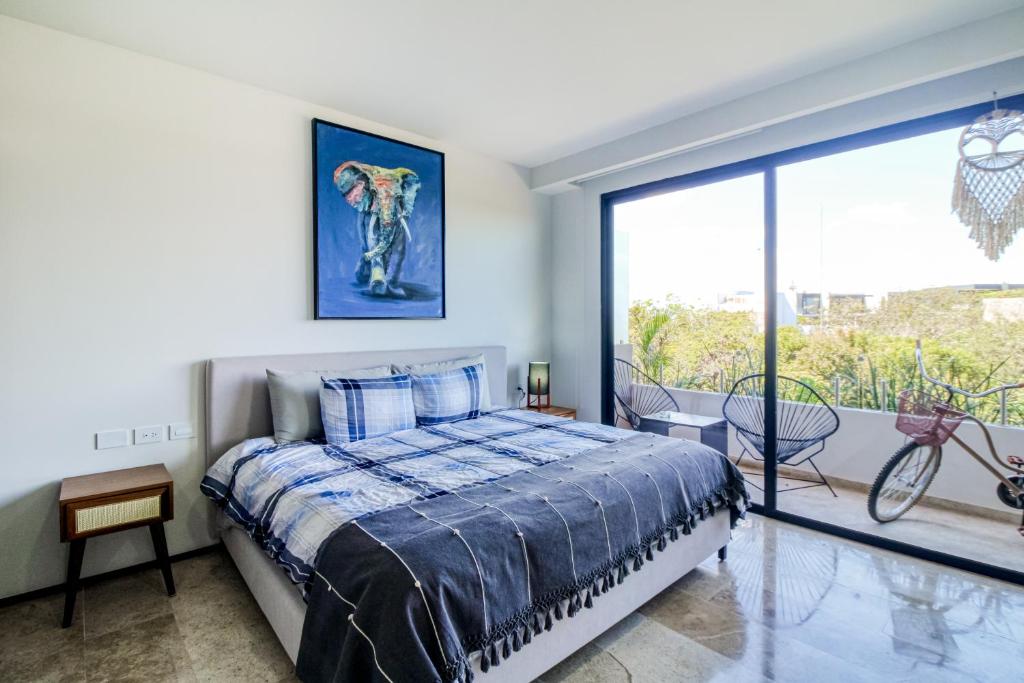 a bedroom with a bed and a large window at Menesse Tulum #327, Downtown in Tulum