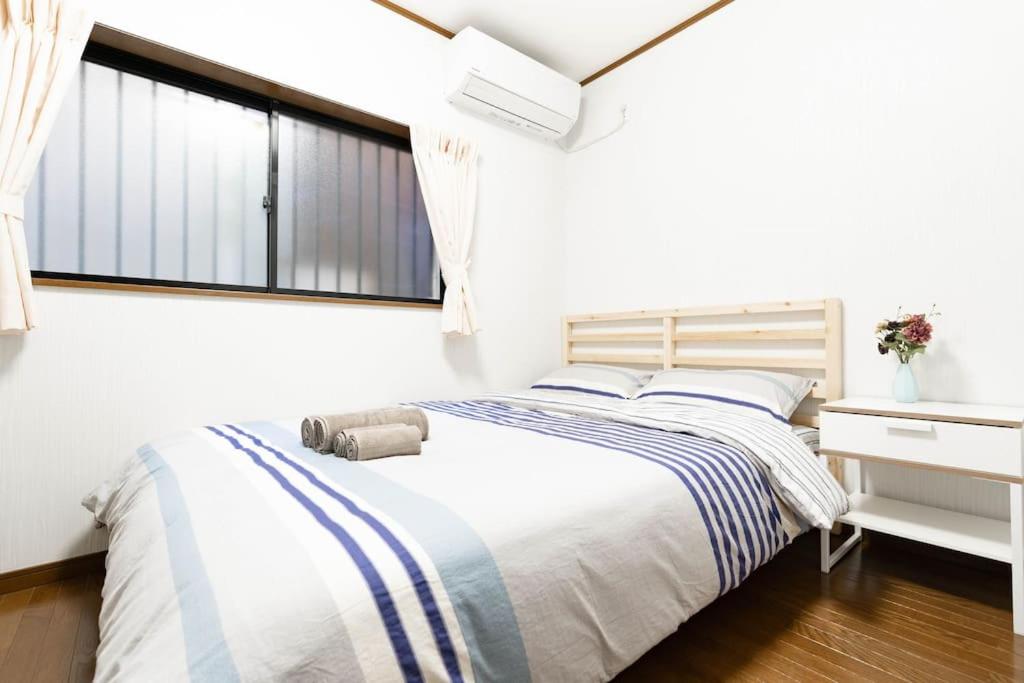 a white bedroom with a bed and a window at 悠の宿 in Osaka