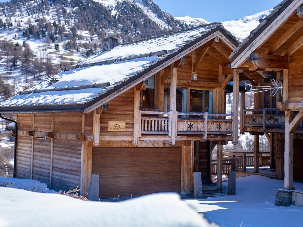 a log cabin with snow on the roof at Chalet Mountainside avec sauna et jacuzzi à 200m des pistes in Vars