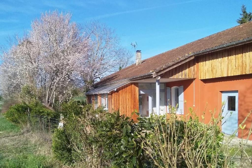 pomarańczowy dom z drzewami i krzakami przed nim w obiekcie Bienvenue au gîte de Claret w mieście Casseneuil