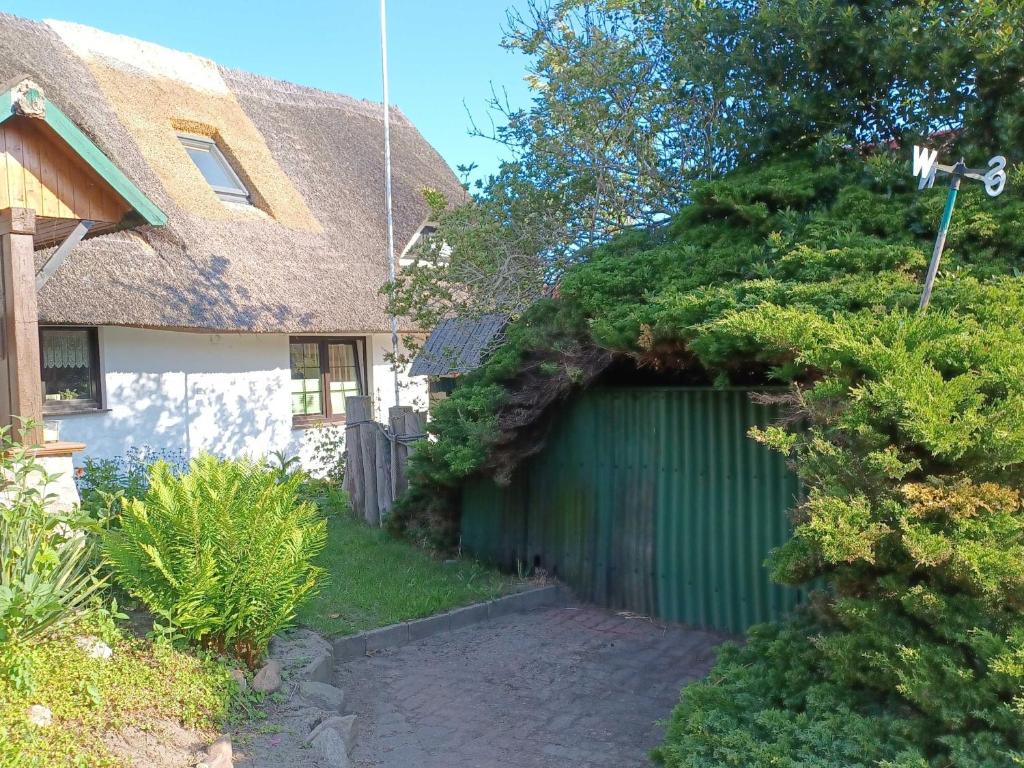 ein Haus mit einer grünen Garage mit Hecke in der Unterkunft Haus 1795 Schwalbennest in Wustrow