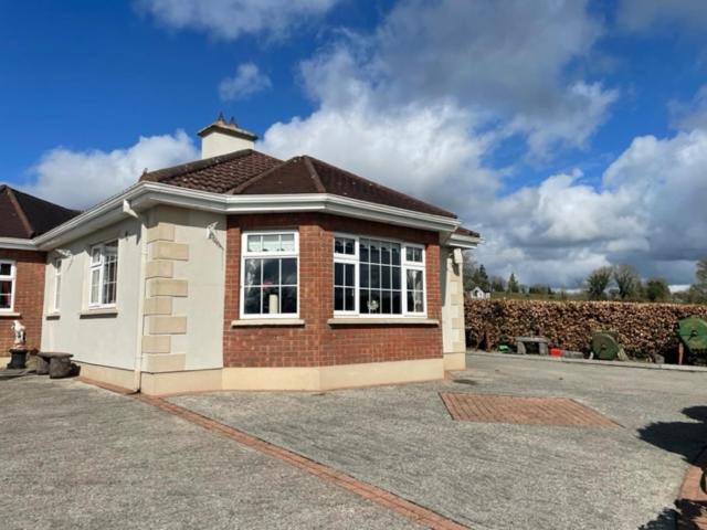 a brick house with a large window in a driveway at Hillside House - Rose Cottage in Ballinamuck