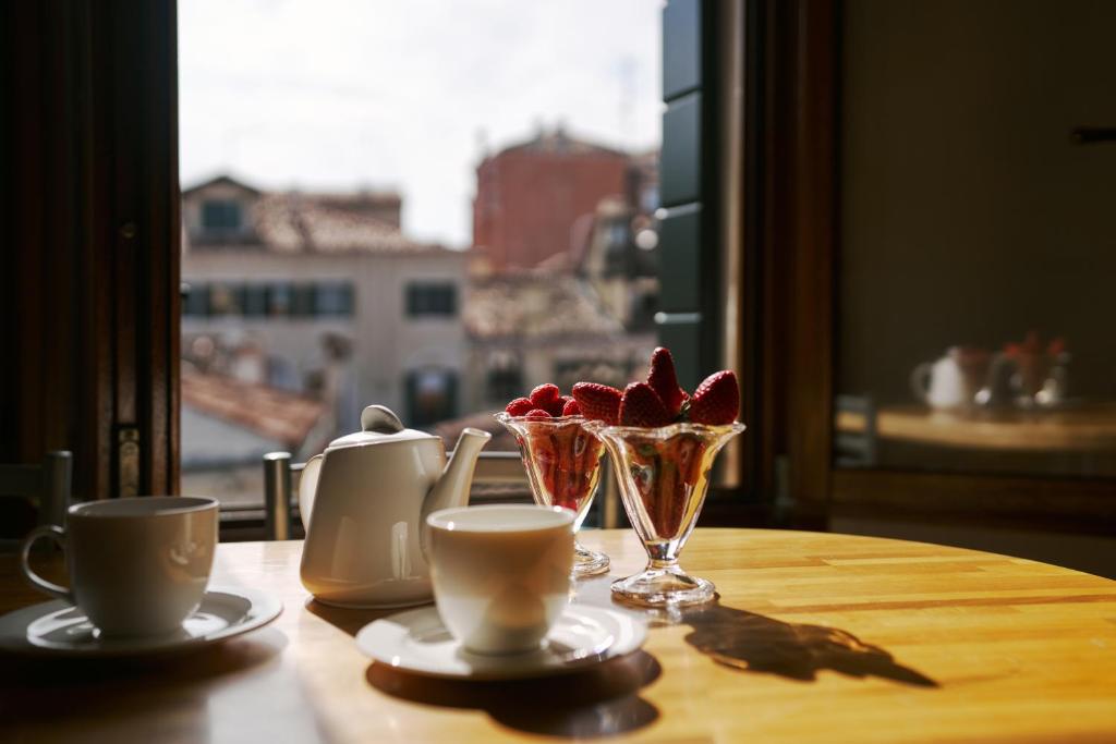 a table with two cups and a vase with flowers in it at Palazzo San Luca in Venice