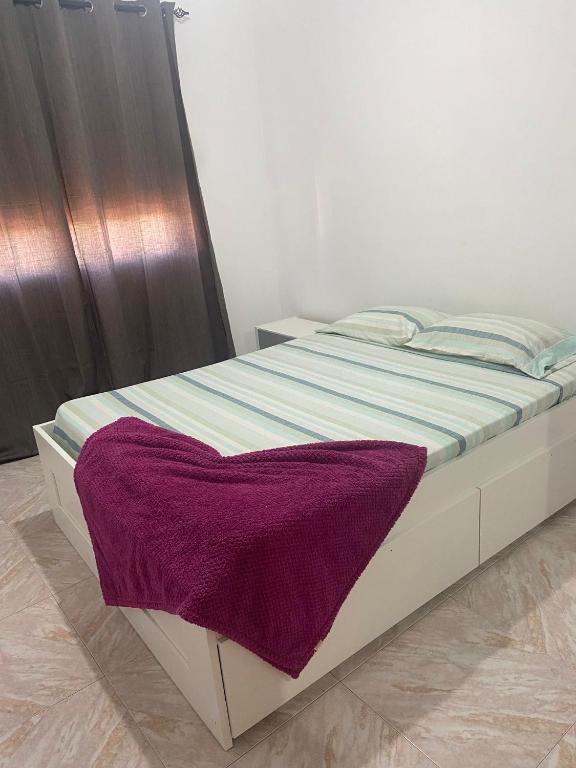 a bed with a purple blanket on top of it at Apartamento com muita luz solar, manhã fresca aqui 
