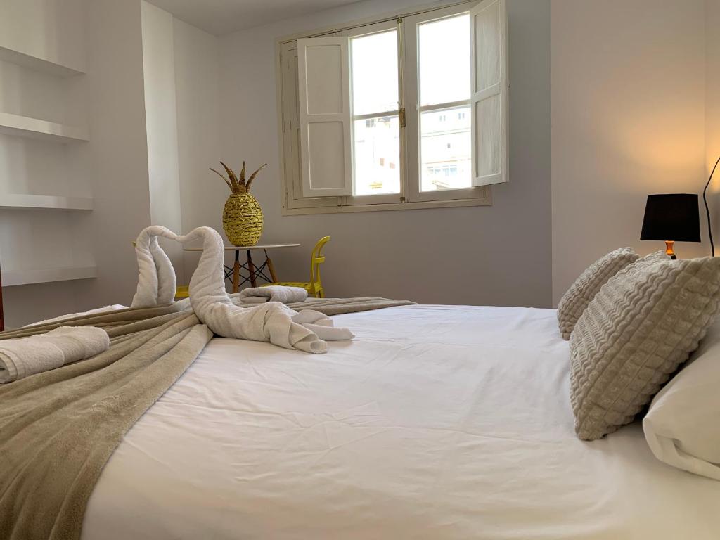 a large white bed with towel animals on it at Doranda Rooms Las Canteras in Las Palmas de Gran Canaria