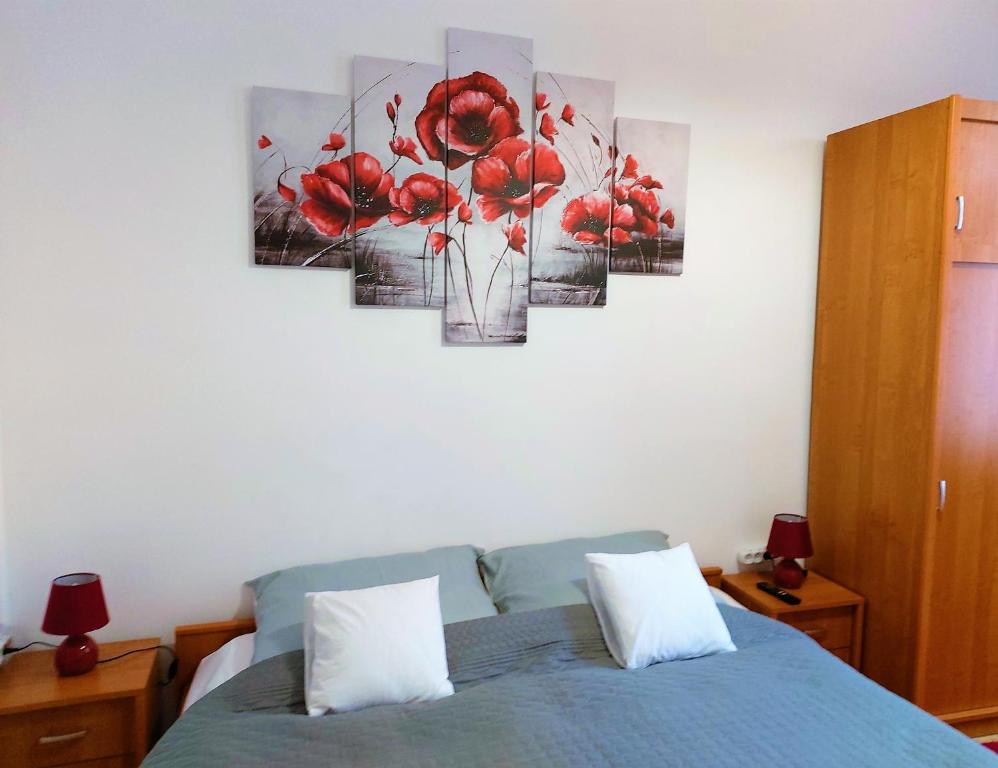 ein Schlafzimmer mit einem Bett mit roten Blumen an der Wand in der Unterkunft Little Hungary Apartment in Budapest