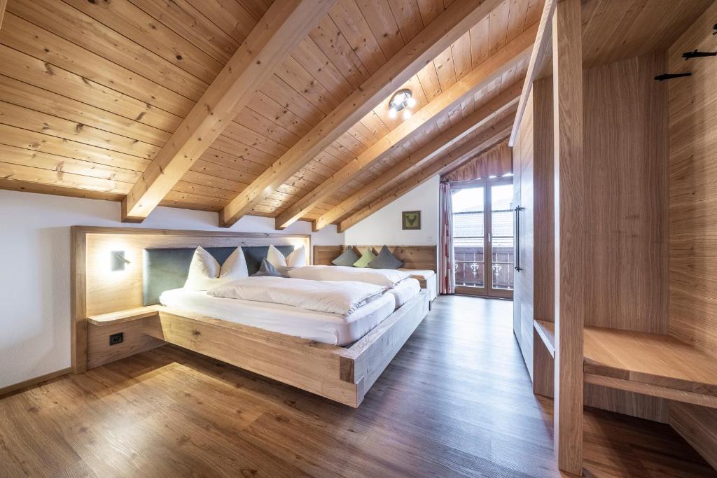 a bedroom with a large bed in a room with wooden ceilings at Ferienwohnungen am Lahnerbach in Lenggries