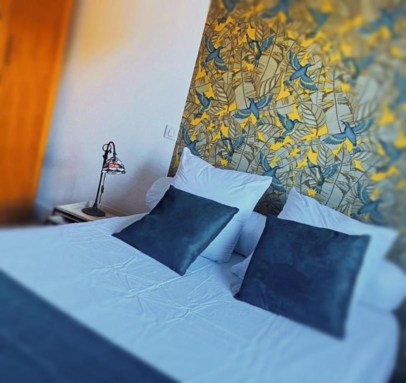 łóżko z niebieskimi poduszkami i obrazem na ścianie w obiekcie Appartement Centre-Ville w Bastii