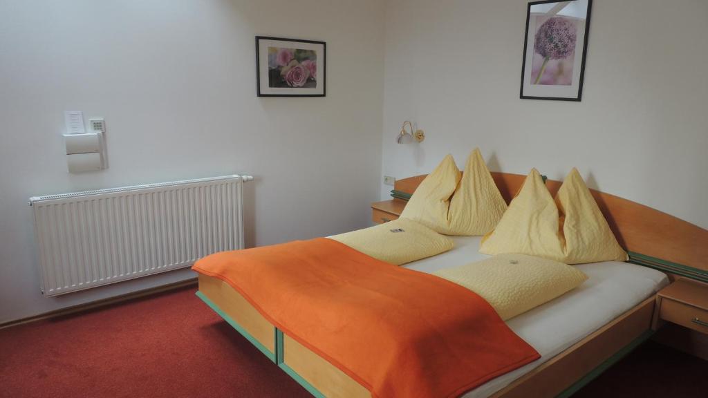 ein Schlafzimmer mit einem Bett mit einer orangefarbenen Decke in der Unterkunft Frühstückspension Barbara in Pöchlarn