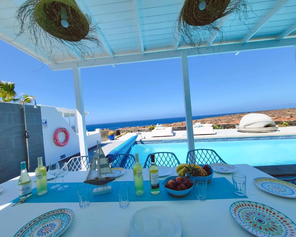 a white table with plates of food and a view of the ocean at Villa Sunset Paradise with panoramic sea view, first line, sunsets in Playa Blanca