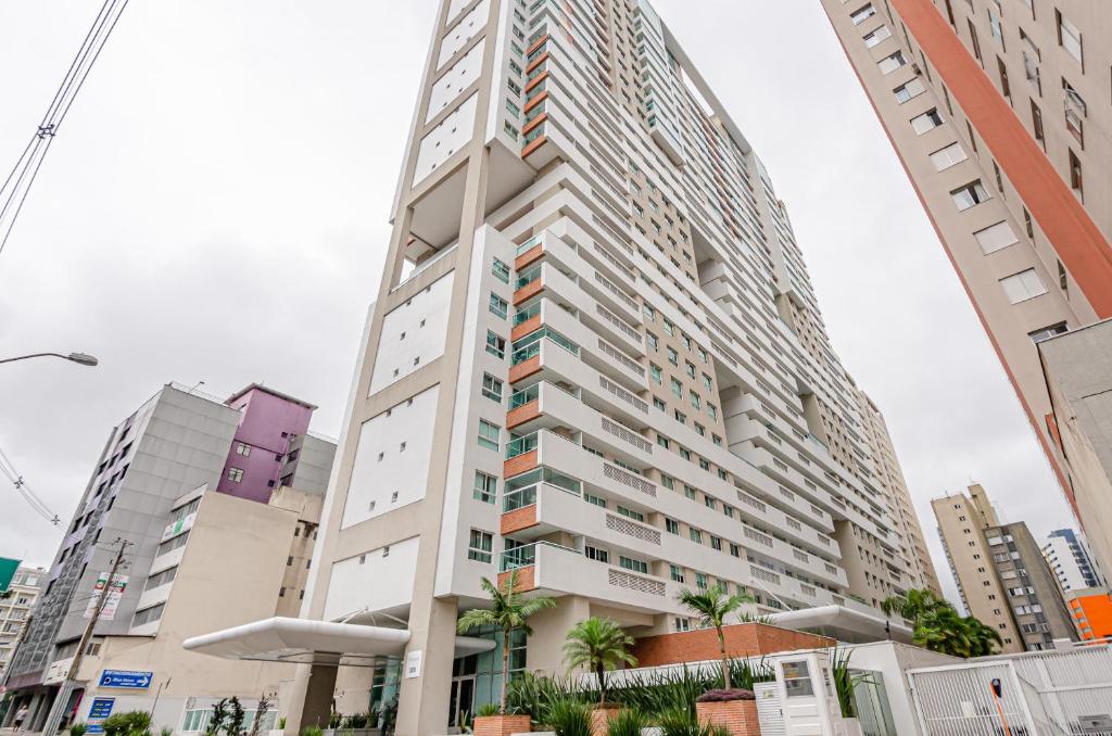 a tall building in a city with buildings at Lifespace Curitiba - Batel - Apartamentos UROOMS in Curitiba