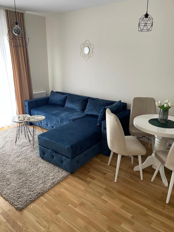 een woonkamer met een blauwe bank en een tafel bij Cvetanov trg LUX 2 in Belgrado