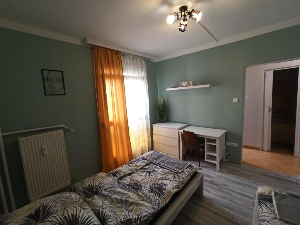 1 dormitorio con cama, escritorio y ventana en Áron Apartman Pécs, en Pécs