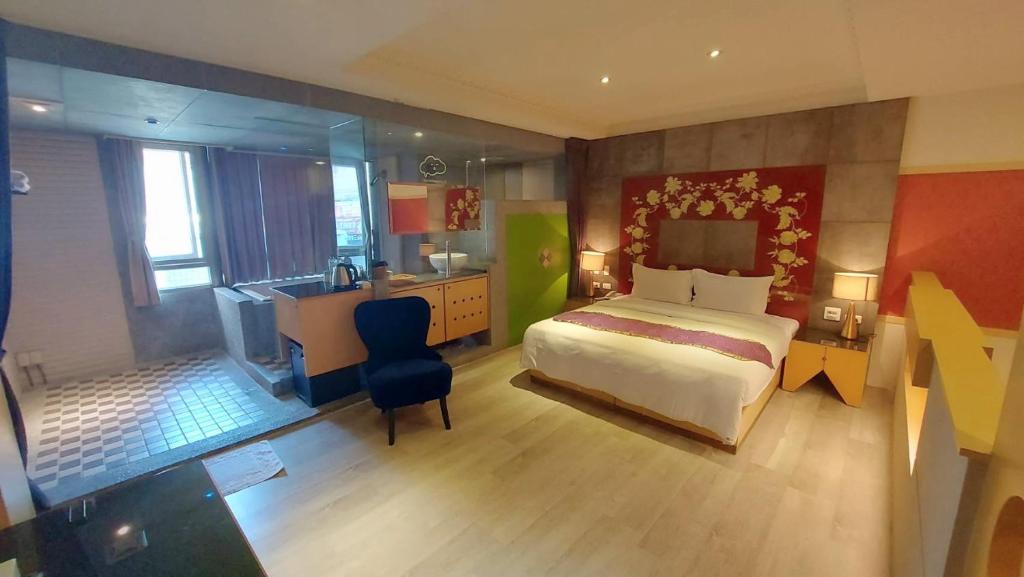 嘉義市にあるJungle City Motelのベッド、デスク、キッチンが備わるホテルルームです。