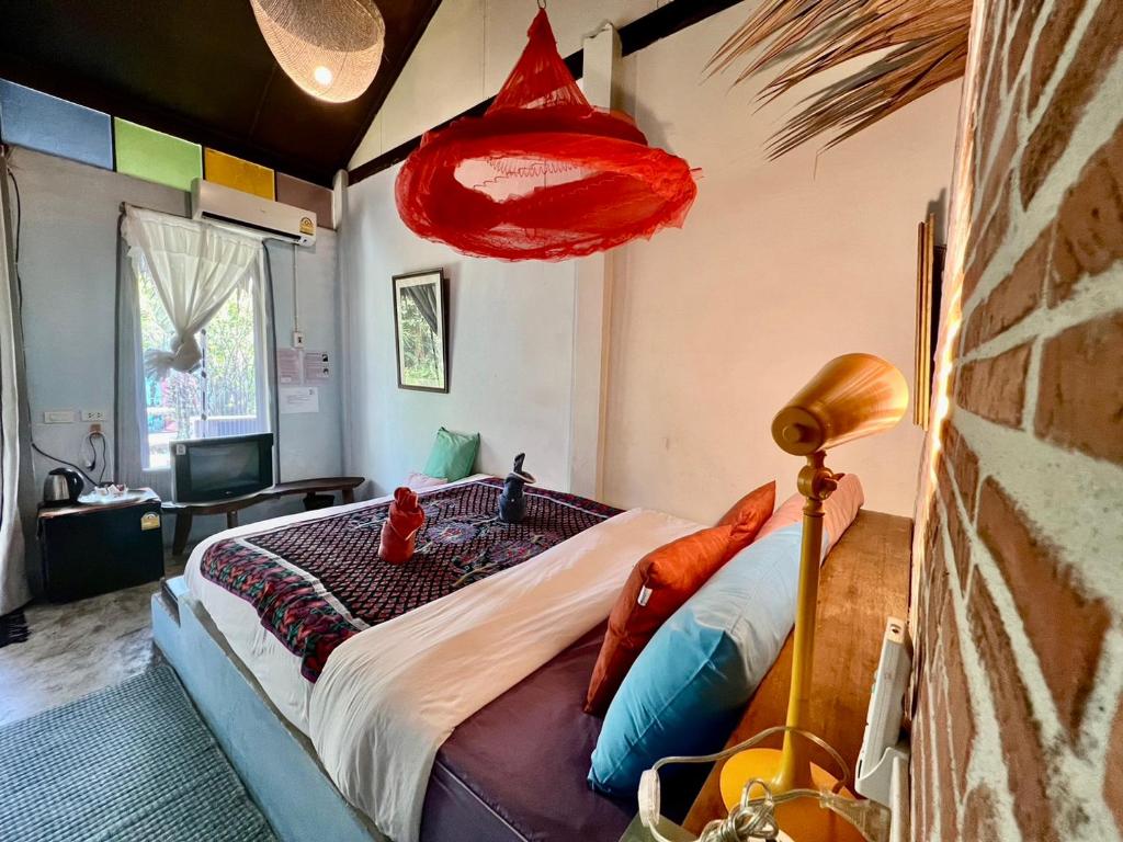 a bedroom with a large bed with a red lamp at Artist's Place Trat in Trat