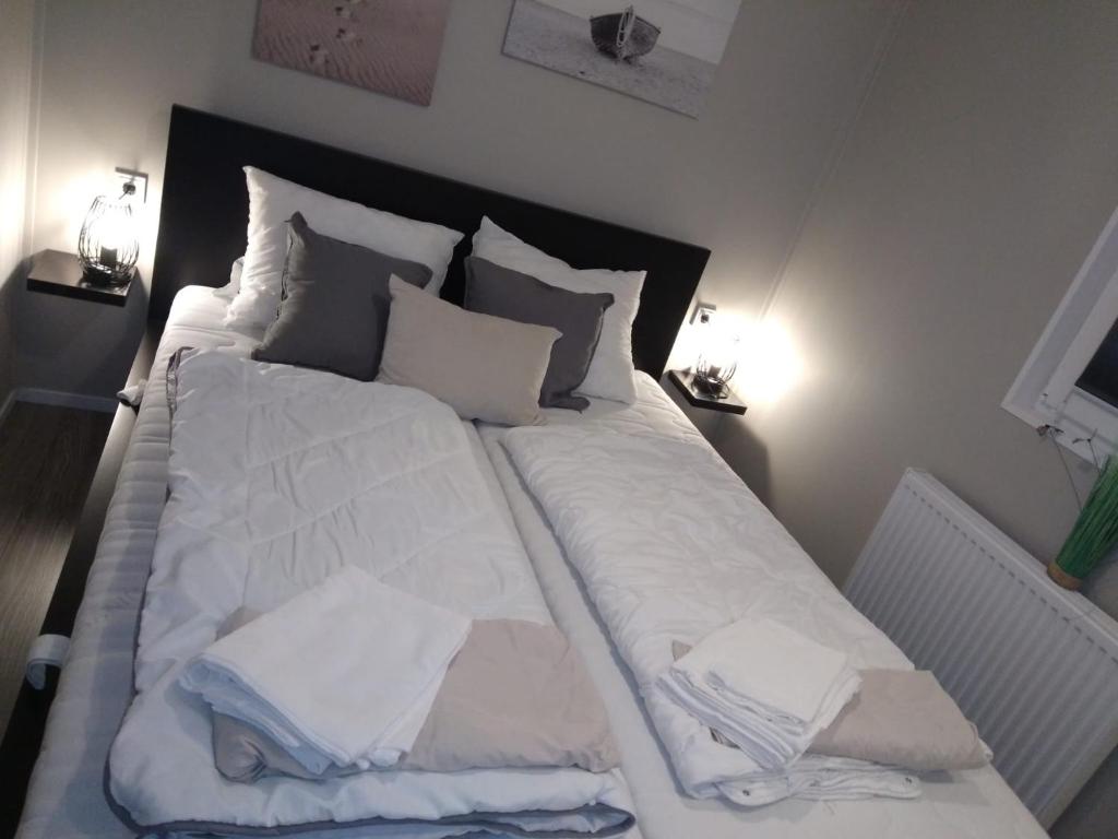ein großes Bett mit weißer Bettwäsche und Kissen darauf in der Unterkunft Ferienhaus / Chalet / Bungalow am See, Holland, Niederlande, Lathum in Lathum