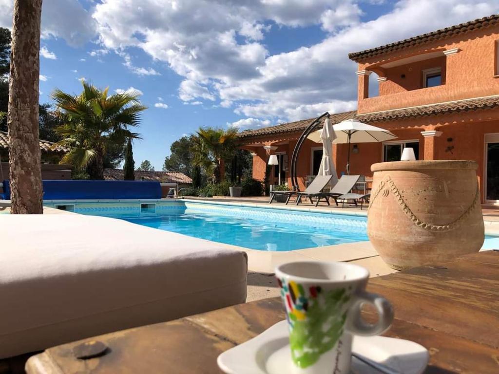 eine Tasse Kaffee auf einem Tisch neben einem Pool in der Unterkunft Villa Catharina in Lorgues